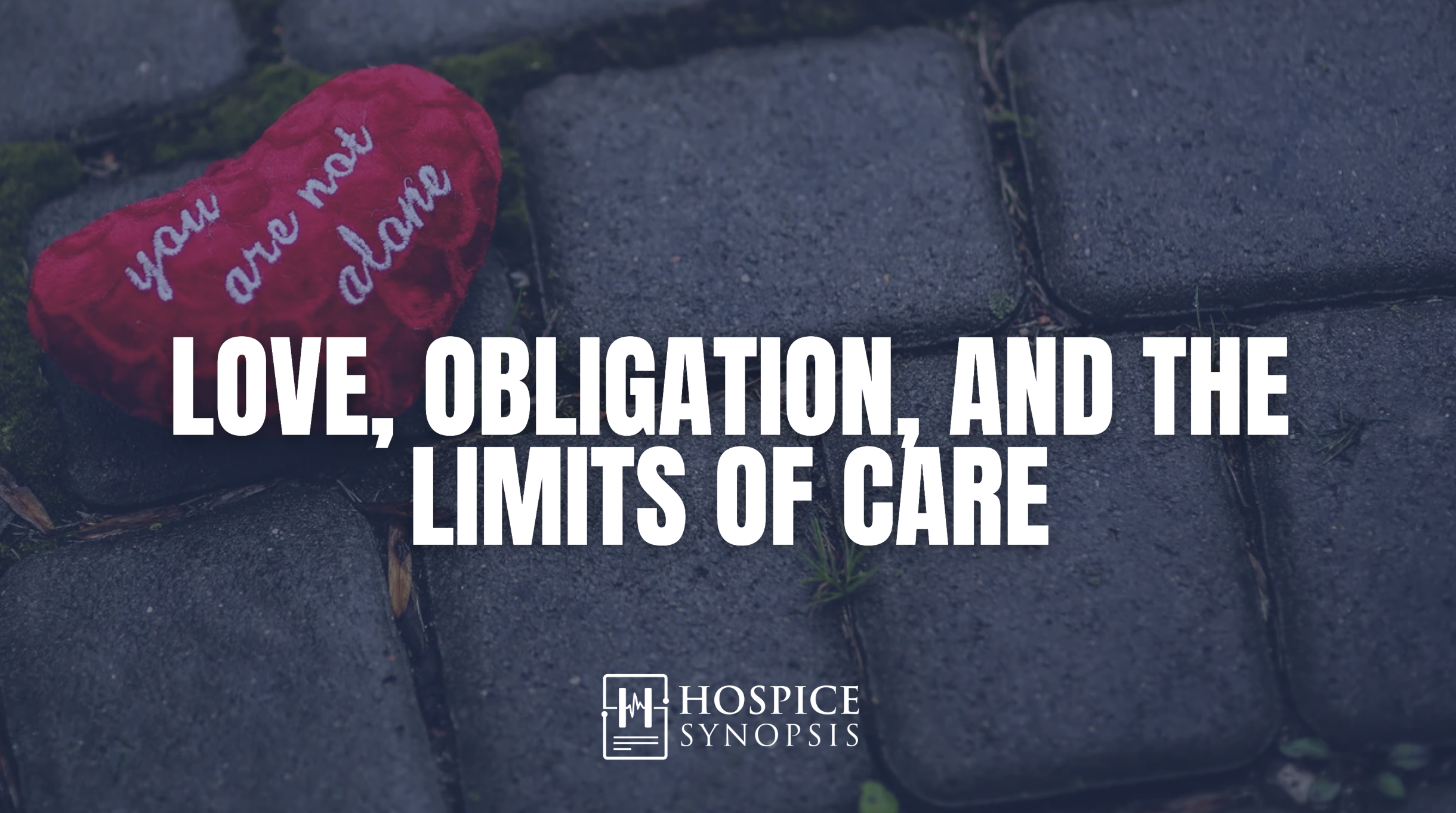A red heart embroidered ‘you are not alone’ rests beside dark stonework beneath the words ‘Love, obligation, and the limits of care.’